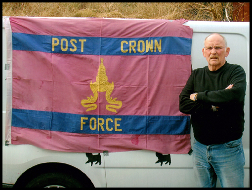 Peter Currie stands beside his 'liberated' Post Crown Force flag.