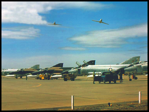 Two RAAF Sabre fighter jets pass over a line of USAF Phantoms